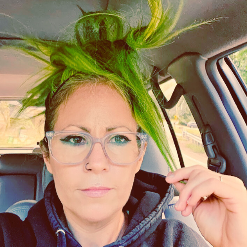Close-up selfie of Meghan Snatchko, local history librarian with bright green spiky hair, in a car.