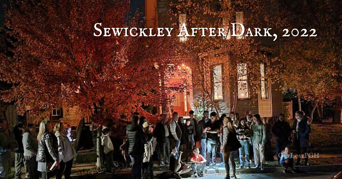 Group gathered on Sewickley After Dark walking tour in 2022, led by Meghan Snatchko of GetLostPGH. Historic house lit at night with fall leaves.